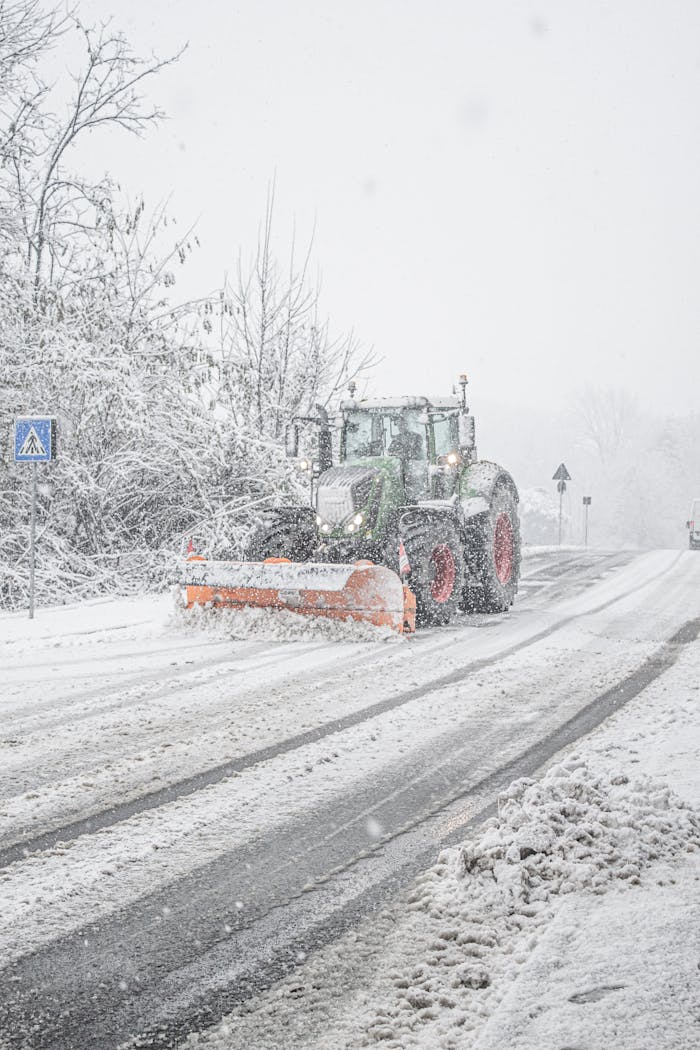Heavy-duty tractor clearing snow-covered roads during winter storm in Laval