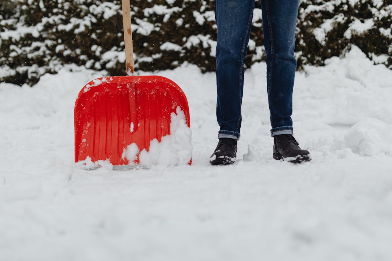 Professional snow removal crew clearing a residential driveway in Laval with a snow shovel